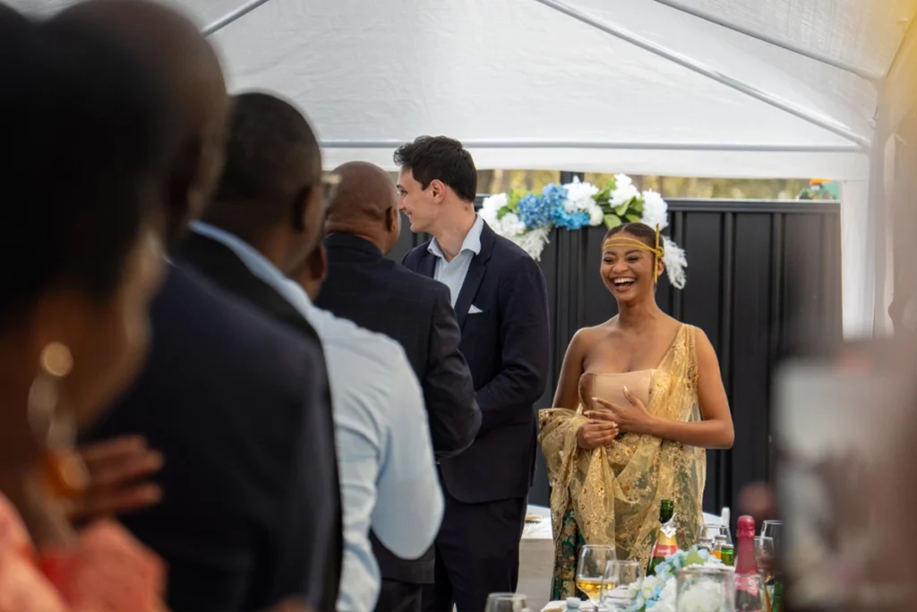 Smiling couple enjoying speeches at a stylish outdoor engagement celebration, photographed by a Brisbane event photographer.