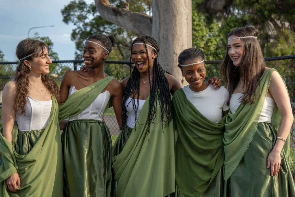 Event photographer in Brisbane captures young women in traditional green attire sharing a joyful moment during a cultural event.