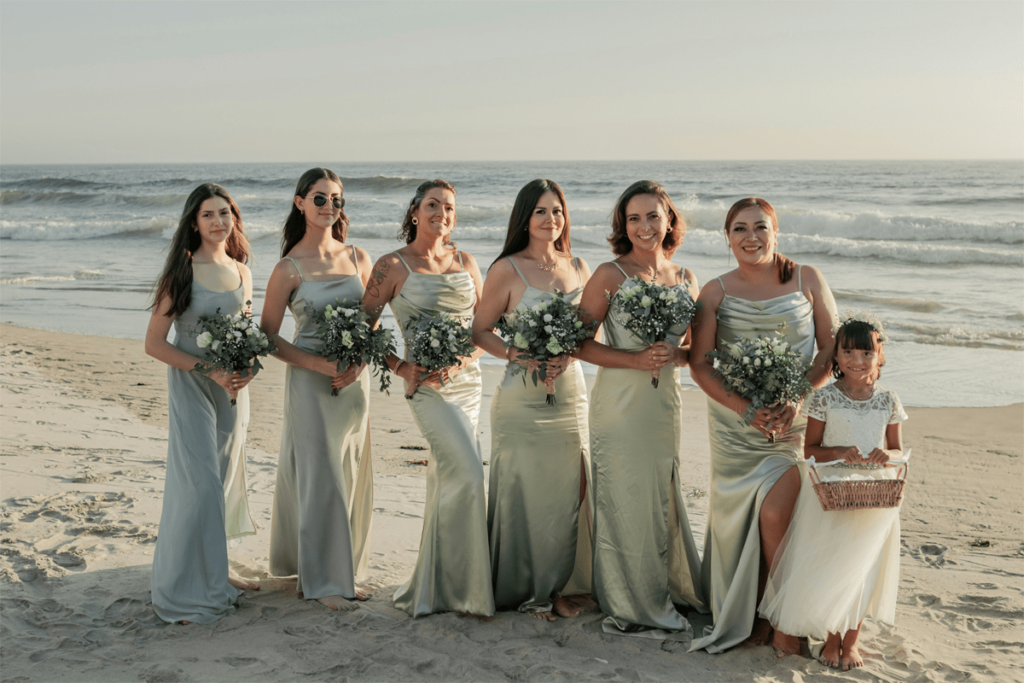 bridesmaids and flower girl smiling and holding bouquets at beach wedding in Brisbane