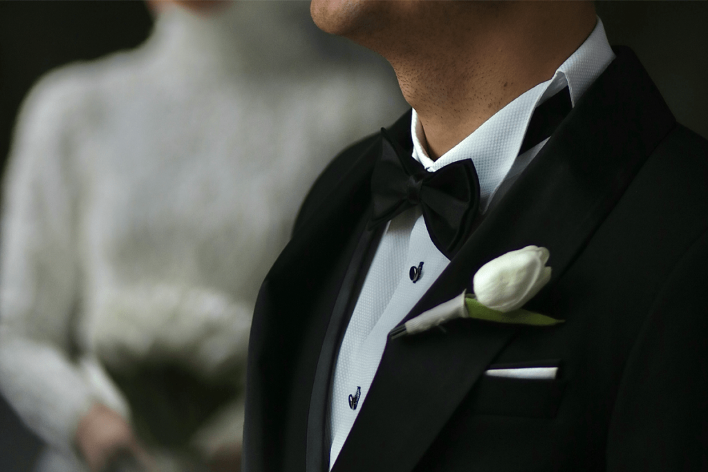groom in classic black wedding tuxedo with white boutonniere and bow tie