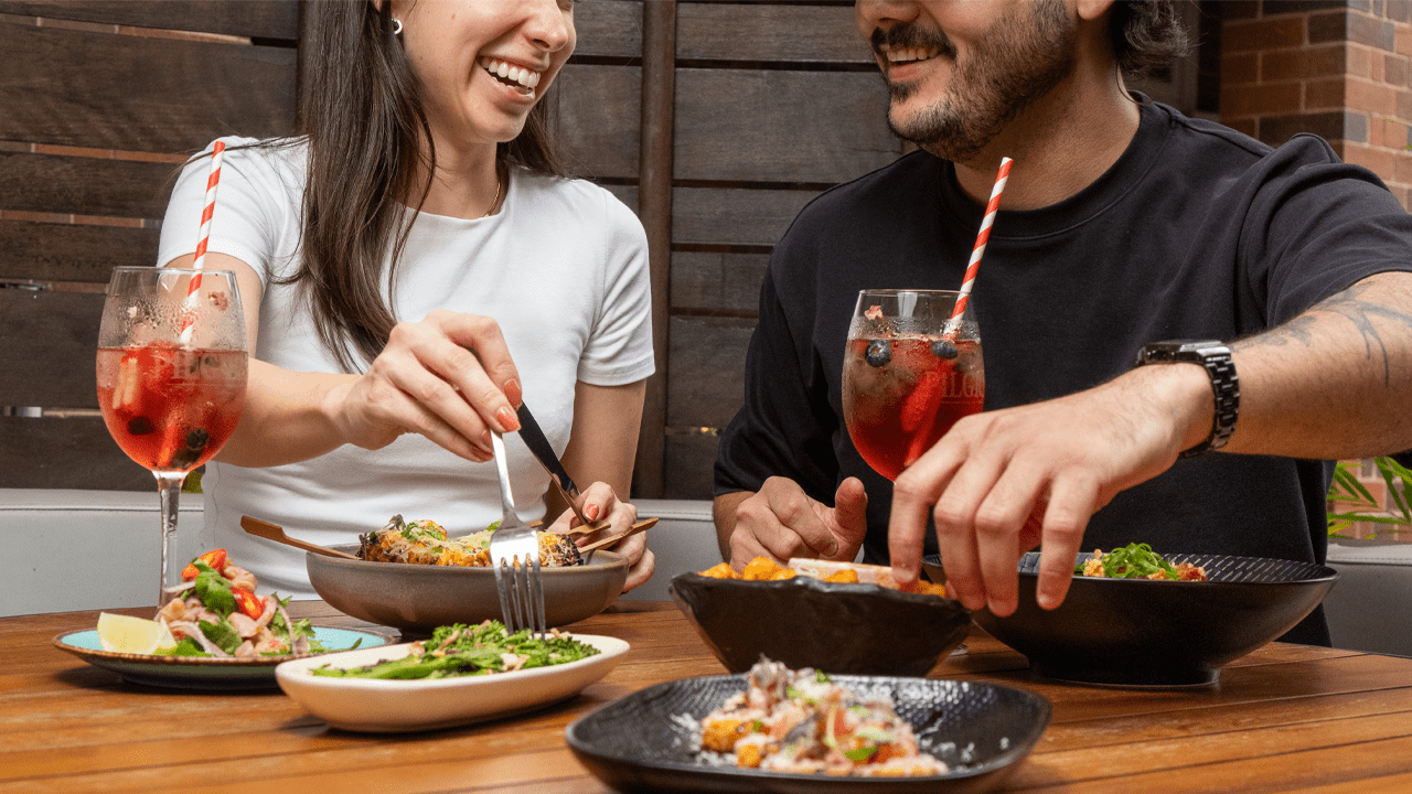 Couple enjoying dinner and cocktails, lifestyle commercial photography for restaurant marketing.