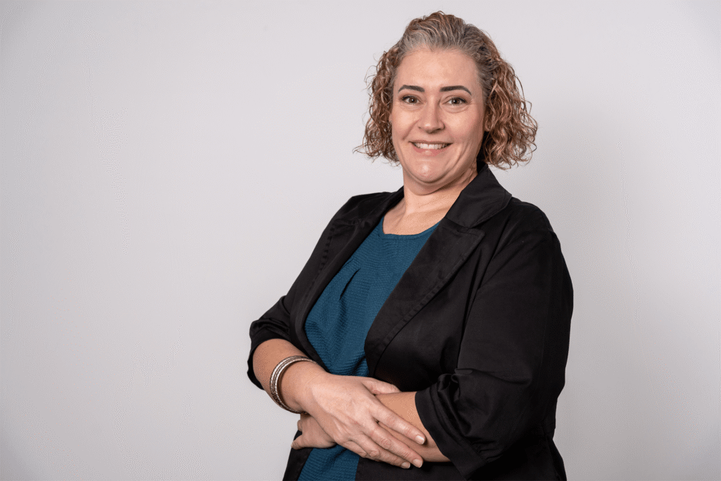 Same woman in black blazer over teal dress, arms crossed and smiling. Casual corporate portrait by Brisbane headshot photographer.
